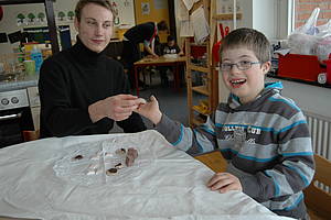 Ein Schüler und der Zivi sitzen am Tisch, zwischen ihnen ist "Schokolade" ausgebreitet
