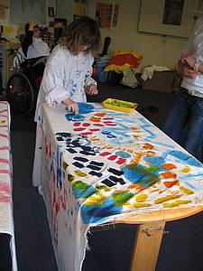 Eine Schülerin bemalt weißen Stoff mit bunten Farben.
